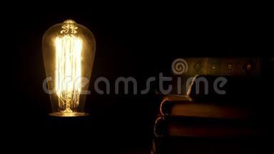 老式灯泡在<strong>复古</strong>书附近的黑暗中开关。