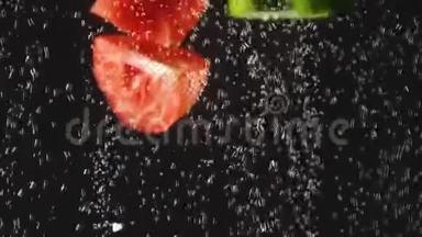 黄瓜和番茄片溅在<strong>水中</strong>的黑色背景。 有气泡的<strong>水中</strong>新鲜蔬菜