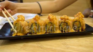 女人从黑色盘子里拿出新鲜的寿司三文鱼卷。 日本菜式