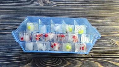 男人用新鲜的浆果从蓝色塑料模具中扔出冰块，在木桌上放冰块。
