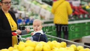 年轻的母亲带着婴儿在超市购物。 <strong>孩子</strong>高兴地看着柠檬，<strong>孩子</strong>的<strong>成长</strong>