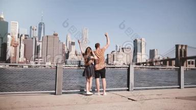 幸福的白种人情侣拥抱在一起，双臂高举在纽约曼哈顿迷人的天际线上，慢条斯理地走着