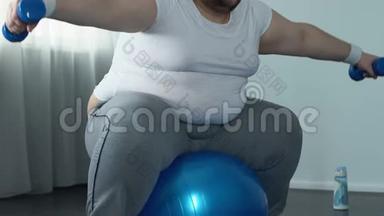 穿着运动服的男运动员举起哑铃坐在健身球上，减肥