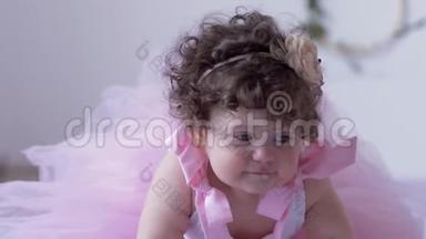 孩子们`拍照环节，一个大眼睛的小女孩，一头卷发，穿着粉色连衣裙，在白色的摄影棚里摆姿势