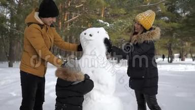 幸福的家庭妈妈，爸爸和儿子正在冬天的城市公园堆雪人。