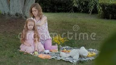 快乐的母亲为<strong>女儿</strong>梳头。日落时分，<strong>一家人</strong>在城市公园野餐。