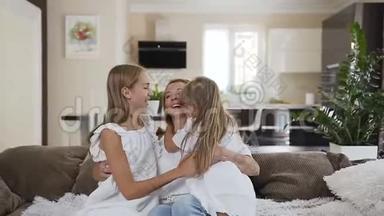 幸福的<strong>一家人</strong>坐在客厅的沙发上。 妈妈和她的两个<strong>女儿</strong>坐在沙发上玩得很开心