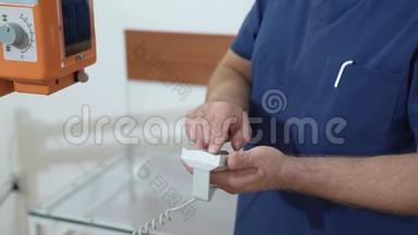 一位男医生使用遥控器调整X光机.. 把`的手拿在医用衣服上