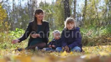 在一个阳光明媚的秋日，带着孩子扔树叶的年轻妈妈一家在公园里放松。 慢动作。 3840x2160。 4K.