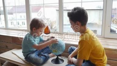 两个男孩用地球仪研究地球的地理。
