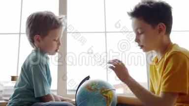两个男孩用地球仪研究地球的地理。