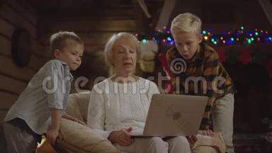 圣诞夜带着两个孙子在笔记本电脑上做视频翻译的<strong>老太太</strong>