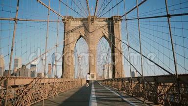 在阳光明媚的<strong>夏日</strong>，男运动员沿着纽约布鲁克林<strong>大</strong>桥跑步。 美丽建筑低角度拍摄4K..