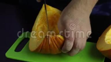 一个人用刀子在切割板上切南瓜。 南瓜是橙色的。 世界素食日