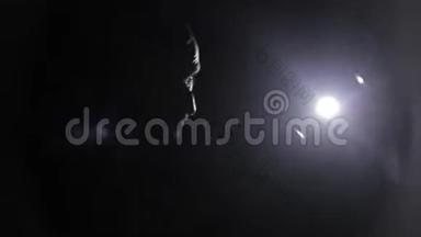拳击手戴拳击手套与教练练习拳打脚踢的男拳击手的特写。 黑暗的背景。 照相机灯光反射
