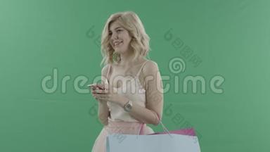 有魅力的<strong>女人</strong>带着智能手机和<strong>包包</strong>在绿色屏幕上迎接别人