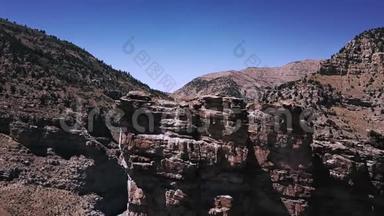 在晴朗的日子里，无人机在巨大的岩石上飞行，以揭示出在高山峡谷山脊之间的美丽的公路道路。