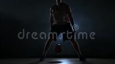 篮球<strong>运动</strong>员在球场上运球，球在黑暗的房间里，背光在<strong>烟雾</strong>中缓慢<strong>运动</strong>