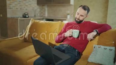 留胡子的人在家里用笔记本电脑时，喝咖啡或<strong>茶会</strong>暂停。 4k个镜头