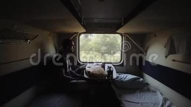 一位年轻的男乘客早上坐<strong>火车车厢</strong>旅行。 他看着窗户，想了想