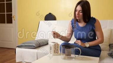 一个年轻的女孩把茶倒进茶壶里焊接。 茶饮