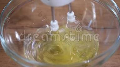 在玻璃碗里打蛋白质。 搅拌碗中电动搅拌器搅拌蛋白的过程。