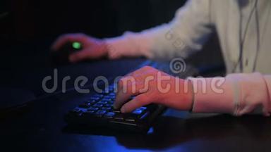 游戏玩家`键盘上的双手特写，积极按下按钮，在线播放MMO游戏。 背景为霓虹灯