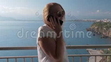 一位白发苍苍的女士在<strong>海边</strong>的一个<strong>酒店</strong>阳台上和一个电话交谈