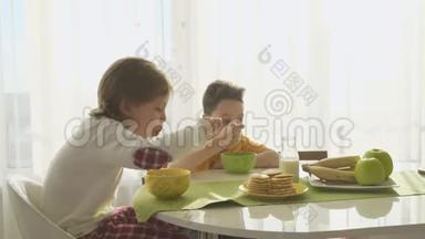 男孩在盘子里倒牛奶和玉米片，两个兄弟在吃早餐