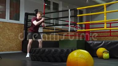 一个人在健身房里用大锤<strong>敲打</strong>轮胎。