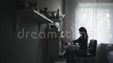 一位成功的年轻女孩坐在家里的桌子旁<strong>翻阅</strong>一些报纸的侧景画像