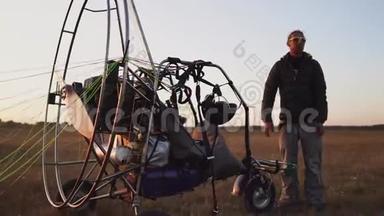 一名驾驶机动滑翔伞的男子将降落伞连接到滑翔伞的身体上，准备飞行和检查