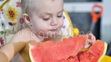 小宝宝在厨房的儿童桌上吃一块西瓜，然后微笑着摇头，近距离观看