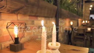 晚餐桌上燃着白色的蜡烛，在晚上的餐厅里进行浪漫的约会。 为浪漫晚餐点燃蜡烛