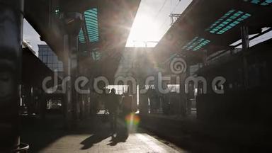 在最后的阳光下，在火车站的站台上告别年轻的爱人。 年轻的剪影