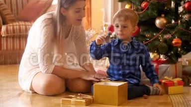 4k段快乐欢笑的小男孩<strong>坐在</strong>圣诞<strong>树下</strong>，从礼盒里拿出玩具