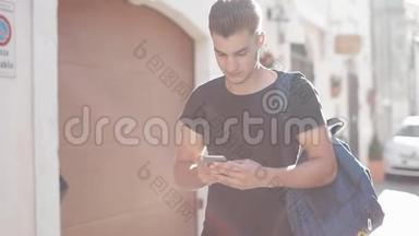 一位英俊的年轻人在智能手机<strong>上</strong>冲浪，在城里<strong>走来走去</strong>。 阳光明媚的背景。 背景模糊