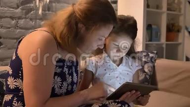 年轻女子<strong>带</strong>着<strong>小孩</strong>使用平板电脑，坐在沙发上的现代家庭，家庭观念，室内