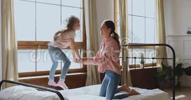 快乐<strong>活泼</strong>的小女孩在床上蹦蹦跳跳地和妈妈玩耍