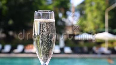 度假期间，在豪华度假酒店的泳池边，为客人提供近景的白色香槟或普罗塞克玻璃。 提供起泡葡萄酒