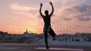 夏日夕阳西下，瑜伽女孩站在屋顶上摆姿势，健康的生活方式，放松的理念，冥想的理念
