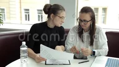 戴眼镜的<strong>两个</strong>商务女孩讨论商业想法，并签订合同。 工作，平板<strong>电脑</strong>，笔记本<strong>电脑</strong>，商务