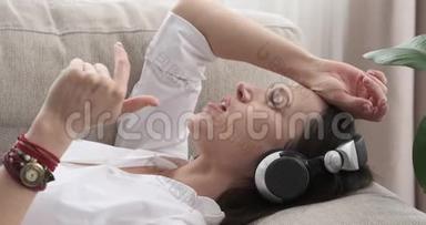 女人躺在沙发上用耳机唱<strong>歌听歌</strong>