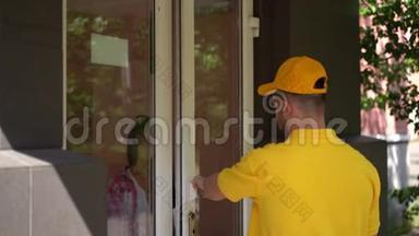 穿黄色制服的快递员在门口给女人送披萨盒。