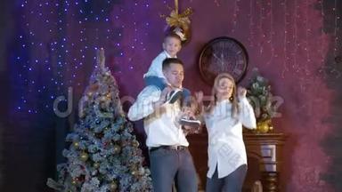 年轻的父母和他们的孩子在圣诞树附近跳舞。