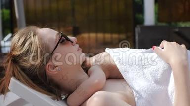 年轻妈妈和小女孩睡在露天游泳池的休息室里
