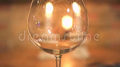在燃烧的蜡烛背景上倒空酒杯。 用蜡烛把酒杯放在晚宴桌上.