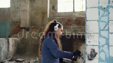 集中妇女正在废弃工业建筑内用喷漆涂鸦装饰旧的破损<strong>柱子</strong>