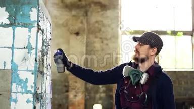 英俊的城市艺术家正<strong>忙着</strong>在废弃的房子里用耳塞油漆装饰脏损坏的柱子。 创造