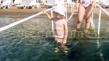 4k视频：带着母亲在海水中漫步的带栏杆的儿童微笑视频
